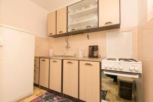 eine Küche mit Holzschränken und einem weißen Herd mit Backofen in der Unterkunft Apartments Visnja in Primošten