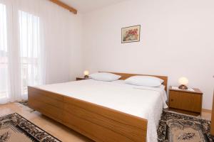 a bedroom with a large bed with white sheets at Apartments Visnja in Primošten