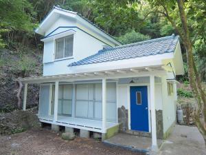 una piccola casa blu e bianca con una porta blu di Oku Cottage - walk to Ohama Beach - Max 4 ppl a Shimoda