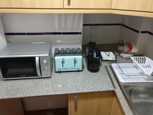 a kitchen counter with a microwave and a stove at Casa da Avó Alsira 2 in Évora