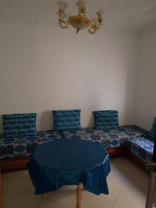 Zimmer mit einem Bett mit blauen Kissen und einem Tisch in der Unterkunft joli appartement 4 chambres in Oujda