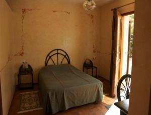 a bedroom with a bed and two chairs and a window at Chambres d'Hôtes Les Pierries in Vézannes