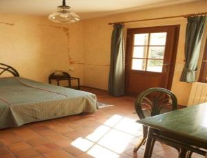 a bedroom with a bed and a table and a window at Chambres d'Hôtes Les Pierries in Vézannes