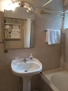 a bathroom with a sink and a tub and a mirror at Apart Hotel Aleman in Puerto Montt