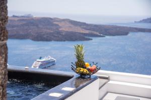 a bowl of fruit on a balcony with a cruise ship at NK Cave House Villa in Fira