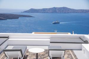 a balcony with a view of the water and a boat at NK Cave House Villa in Fira