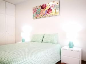 a bedroom with a bed and a painting on the wall at Peniche's Blue & White in Peniche