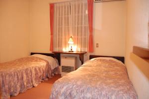 1 dormitorio con 2 camas, ventana y mesa en Petit Hotel and Restaurant Air Mail en Hakuba