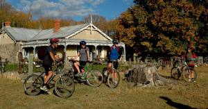 grupa ludzi jeżdżących rowerami przed domem w obiekcie Peter's Farm Lodge w mieście Waipiata