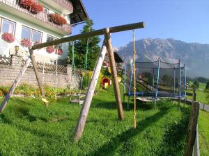 a swing set in a yard next to a house at Hotel Tischlbergerhof in Ramsau am Dachstein