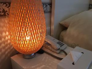 une lampe orange sur une table à côté d'un lit dans l'établissement Business Hotel La Firenze, à Tokyo