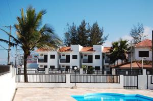 a building with a fence and a swimming pool at Hotel Nossa Senhora do Carmo in Ilha Comprida