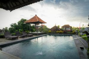 a swimming pool with chairs and a gazebo at Ina Inn in Ubud