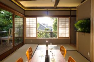 a dining room with a table and chairs and a window at Machiya Maya Gion in Kyoto