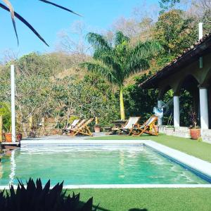a swimming pool with chairs and a house at Casa Andalucia in San Juan del Sur