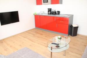 eine Küche mit einem Glastisch und roten Schränken in der Unterkunft Stars Berlin Apartments Zillestraße in Berlin