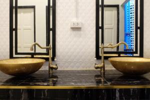 two sinks in a bathroom with two mirrors at The Orientale Hostel in Bangkok