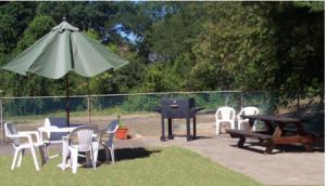 einen Tisch, Stühle, einen Grill und einen Regenschirm in der Unterkunft Shore Hills Motel in Manasquan