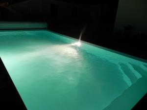 a swimming pool with a light in the water at La clé de vos Rêves in Orthevielle