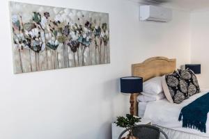 ein Schlafzimmer mit einem Bett und einem Gemälde an der Wand in der Unterkunft The Studio on Balmoral in Durban