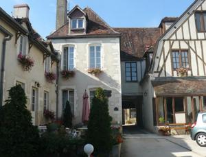 un grupo de edificios con un coche aparcado en la calle en LOGIS HOTEL - Le Relais Saint Vincent, en Ligny-le-Châtel