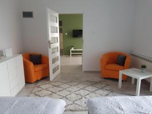Sala de estar con 2 sillas de color naranja y mesa en Pod Jasną Górą Apartament 23, en Częstochowa