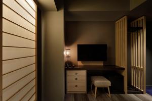 a bedroom with a tv and a dresser with a chair at Hotel Resol Kyoto Kawaramachi Sanjo in Kyoto