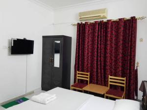 een kamer met een bed en twee stoelen en een televisie bij Sophin Hotel in Sharjah