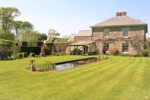 a large brick house with a pond in the yard at Glebe House Cottages in Bude