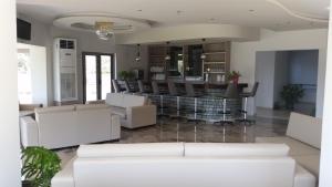 a living room with white furniture and a bar at Saint George Resort in Archangelos