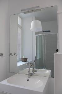 La salle de bains blanche est pourvue d'un lavabo et d'un miroir. dans l'établissement L'authentique - Coeur de ville, à Toulouse