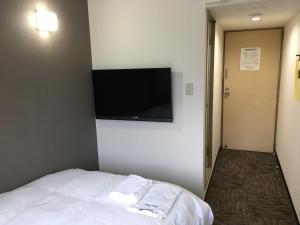 a hotel room with a bed and a flat screen tv at Hotel Tetora Asahikawa Station in Asahikawa