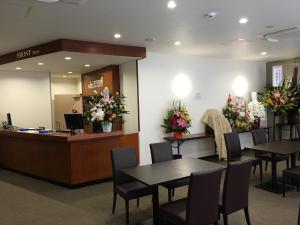 ein Wartezimmer mit Tischen, Stühlen und Blumen in der Unterkunft Hotel Tetora Asahikawa Station in Asahikawa