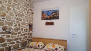 a room with a stone wall and a bed with pillows at Holiday House Popovic in Sućuraj