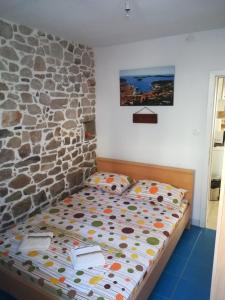 a bed in a room with a stone wall at Holiday House Popovic in Sućuraj