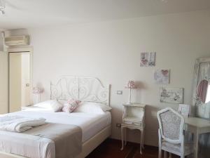 Un dormitorio blanco con una cama blanca y un escritorio. en Villa Montenero, en Cavalcaselle