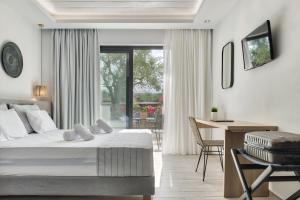 een slaapkamer met een bed en een bureau en een tafel en stoelen bij Dannas Boutique Apartments in Tsilivi