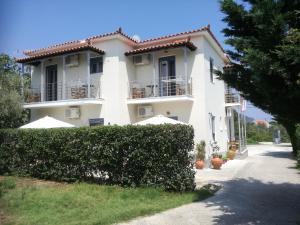 a large white house with a hedge in front of it at Rastoni Guest House Skopelos in Skopelos Town