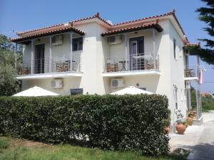a white house with balconies and bushes at Rastoni Guest House Skopelos in Skopelos Town
