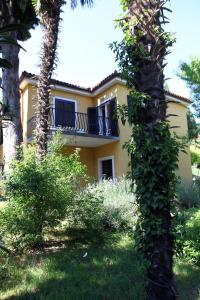 a yellow house with a balcony and a palm tree at Your Rooms in Portoroz TM in Portorož