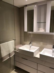a bathroom with two sinks and a mirror and towels at The Docs 2 in Gaborone