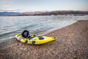 a yellow kayak sitting on a beach next to the water at Hotel Plaza in Pag