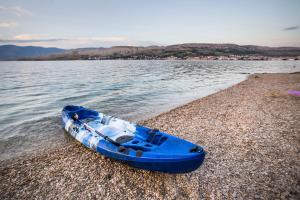 a blue boat sitting on a beach near the water at Hotel Plaza in Pag