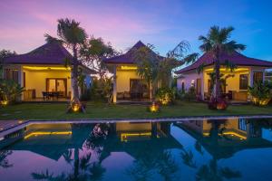 a villa with a swimming pool at night at Bali Mynah Villas Resort in Jimbaran