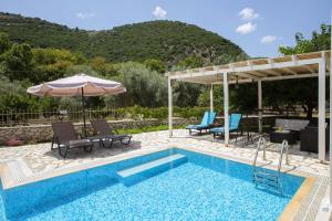 a swimming pool with a patio and an umbrella at Villa Niriides in Lefkada Town