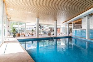 a large swimming pool with chairs and a swimming pool at Hotel Waldhaus am See in Valbella