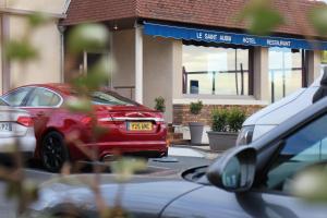 una macchina rossa parcheggiata di fronte a una casa di Saint Aubin Logis Hôtel & Restaurant a Saint-Aubin-sur-Mer