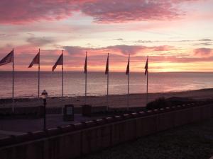 a group of flags on the beach at sunset at Saint Aubin Logis Hôtel & Restaurant in Saint-Aubin-sur-Mer
