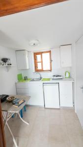 a kitchen with white cabinets and a table and a window at Roulas Apartments in Halki