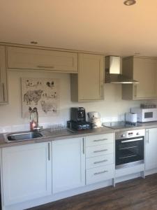 a kitchen with white cabinets and a sink at Adalienes Retreat in Portree